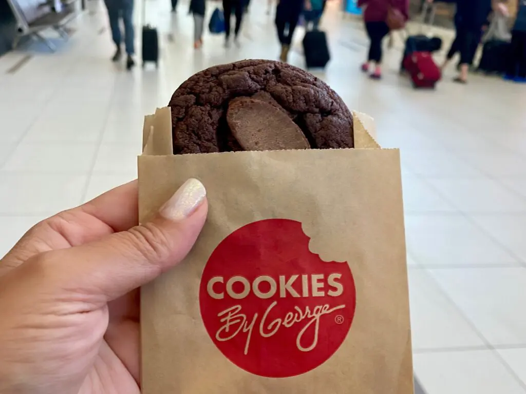 A photo of a hand holding a Cookies By George cookie.