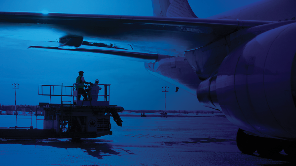 Une photo avec une superposition bleue d'un employé de l'aéroport travaillant dans un avion